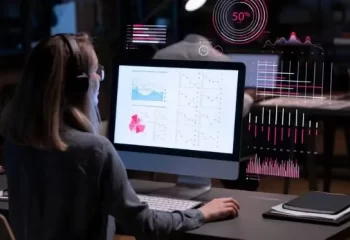 Pessoa analisando gráficos e dados em uma tela de computador com gráficos interativos, representando análise de dados em ambiente de trabalho moderno.