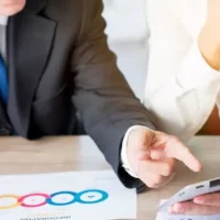 Homem de negócios apontando com o dedo para um tablet digital segurado por seu parceiro no local de trabalho