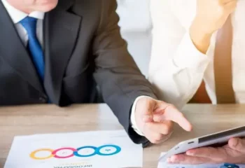 Homem de negócios apontando com o dedo para um tablet digital segurado por seu parceiro no local de trabalho