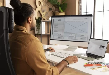 Homem trabalhando em um ambiente de escritório moderno, avaliando designs em telas, ideal para decoração e design de interiores.