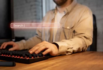 Pessoa usando teclado de computador com uma busca online, representando a importância da autoridade tópica no SEO na era da inteligência artificial.