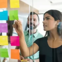 Mulher discutindo post-it com colegas de trabalho em reunião no escritório