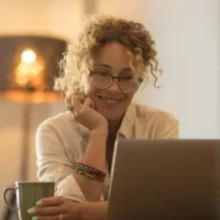 Mulher sorridente trabalhando em laptop em casa.