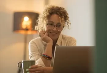 Mulher sorridente trabalhando em laptop em casa.